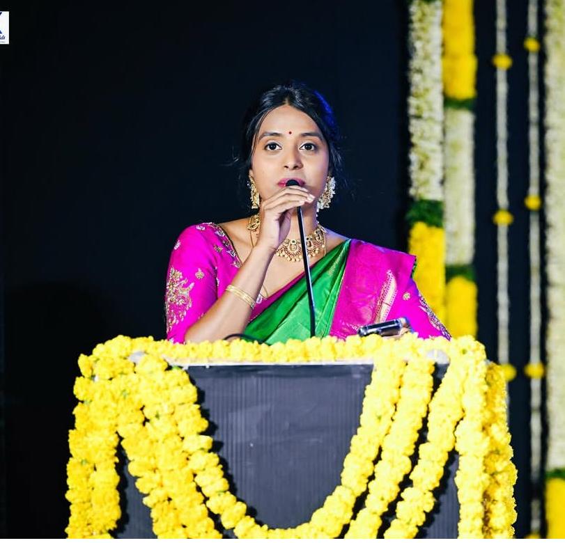 Swetha speaking on stage at a podium